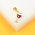 A gold wine glass pendant featuring red enamel rests on a white and yellow surface.