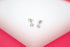 A pair of sparkling solitaire stud earrings rest elegantly on a white display stand.