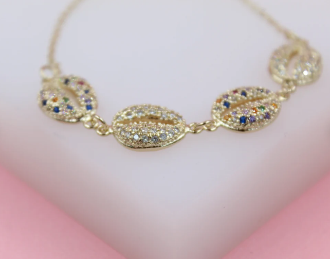 A delicate gold chain bracelet features sparkling shell charms embedded with multicolored cubic zirconia stones.