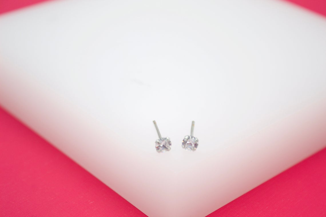 A pair of sparkling cubic zirconia stud earrings rests on a white display surface.