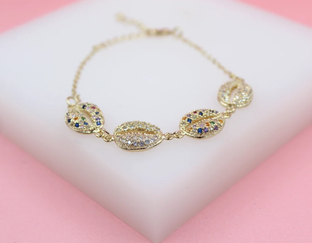 A delicate gold chain bracelet features four shell-shaped charms encrusted with sparkling clear and multicolored zirconia stones.