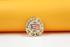 A gold Puerto Rico pendant featuring an enameled flag rests against a warm yellow and white background.