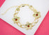 A gold link chain bracelet features three flower-shaped charms adorned with sparkling red crystal centers.