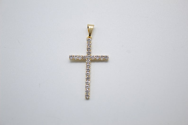 A gold cross pendant encrusted with sparkling diamonds rests on a clean white background.