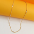 A delicate gold chain necklace sparkles with marquise-cut CZ stones against a bright orange and white backdrop.