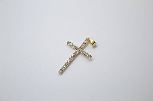 A sparkling gold cross pendant paved with small diamonds lies flat against a plain white background.