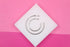 Two sterling silver hoop earrings rest on a white square display against a vibrant pink background.