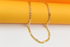 A shiny gold chain necklace rests gracefully against a vibrant yellow and white background.