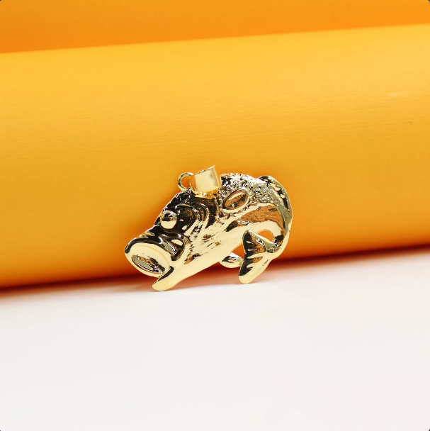 A shiny gold fish pendant rests against a warm orange and white background.