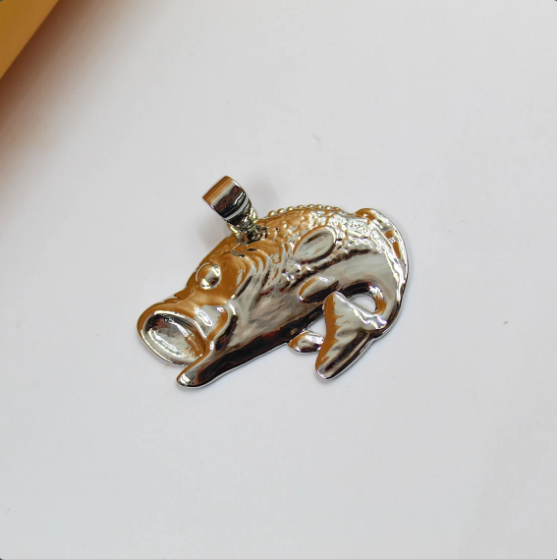 A polished silver bass fish pendant rests on a clean white surface, showcasing detailed scales and an open-mouthed design.