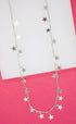 A delicate silver necklace features dangling star charms along its chain against a pink background.