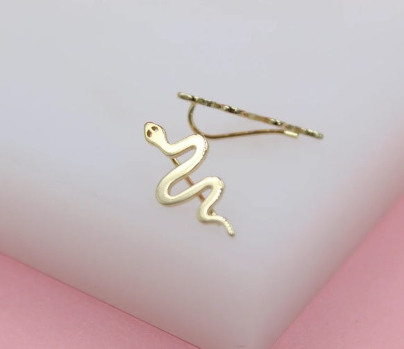 A delicate gold snake ear crawler rests against a soft white and pink background.