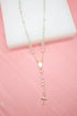 A delicate gold rosary necklace featuring pastel-colored pearl beads rests on a pink and white display surface.