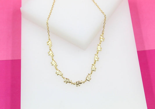 A delicate gold chain necklace featuring miniature elephant charms displays on a white and pink background.