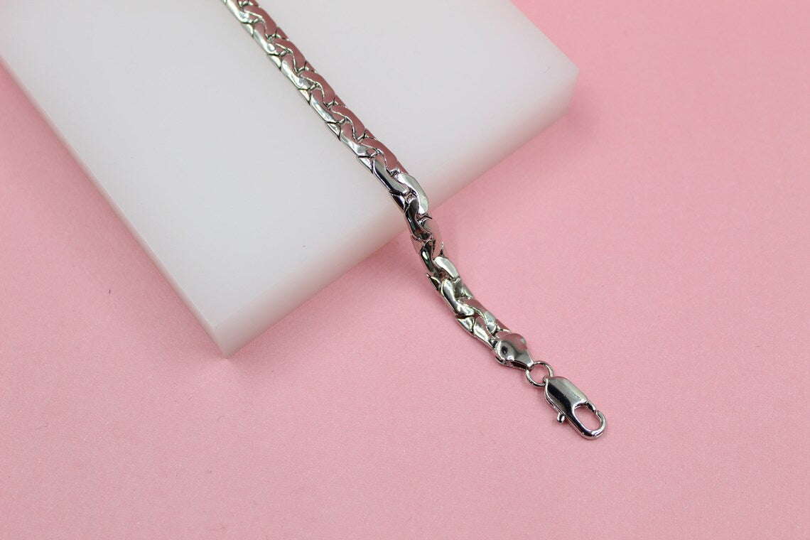 A polished silver link bracelet rests diagonally across a white display block against a soft pink background.
