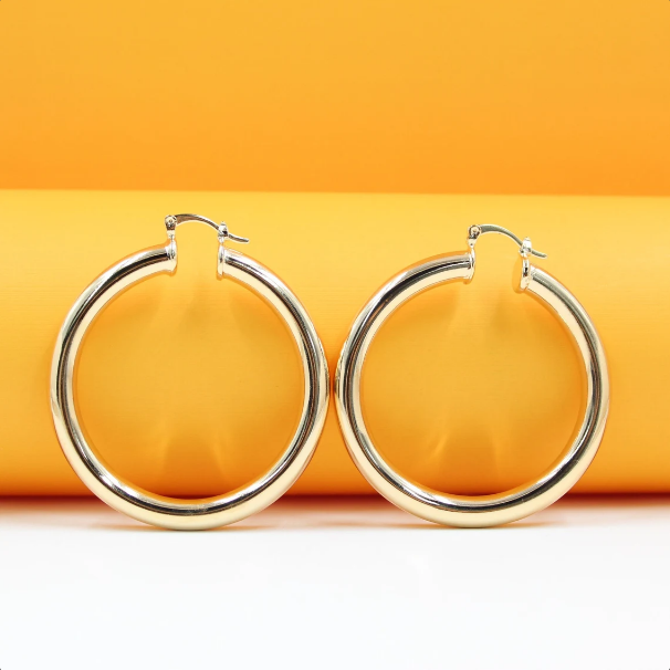 Two polished gold hoop earrings rest against a bright orange and white background.