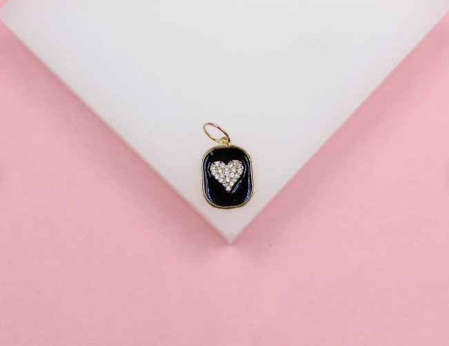 A gold pendant features a black rectangular frame with a sparkling pave-set diamond heart at its center.