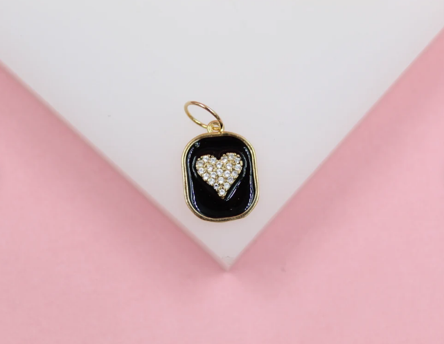 A gold-trimmed rectangular pendant features a glossy black enamel background and a sparkling cubic zirconia heart charm.