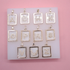 A collection of gold-framed initial pendant necklaces with rhinestone-encrusted letters is displayed on a white board against a pink background.