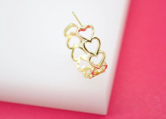 A gold heart hoop earring rests on a white and pink surface.