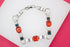 A silver link bracelet featuring vibrant orange gemstone stations rests on a white and pink background.