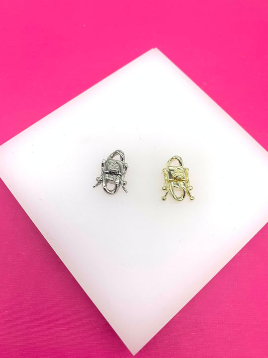 A silver and a gold multi-strand box clasp rest side by side on a white display surface against a vibrant pink background.