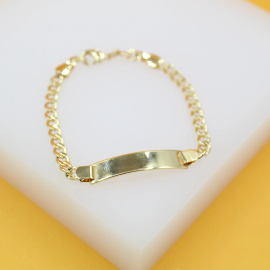A polished gold identification bracelet rests on a clean white display block.