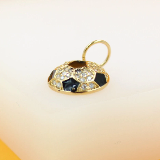 A gold soccer ball pendant features sparkling diamonds and black enamel accents against a plain background.