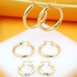 Three pairs of graduated gold hoop earrings hang and display on a white stand against an orange background.