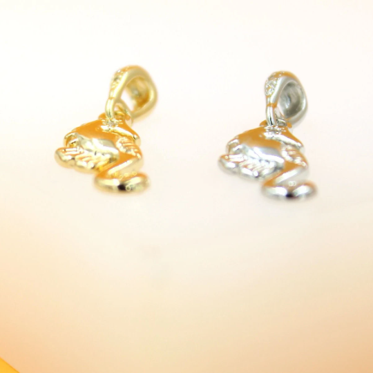 Two gold and silver seahorse pendants rest side by side on a light surface.