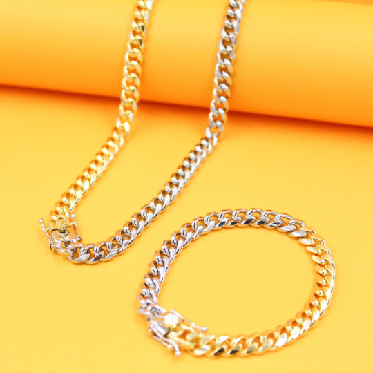 A matching two-tone gold and silver Miami Cuban link chain necklace and bracelet set rests against a bright yellow background.