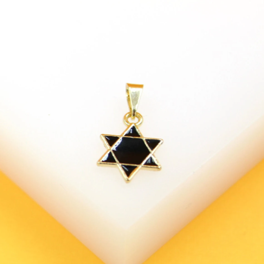 A gold-plated Star of David pendant with black enamel inlay rests on a white display block.
