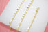 A delicate gold chain bracelet features hanging hexagonal coin charms displayed on a white surface.