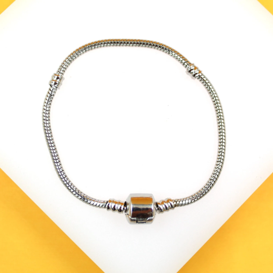 A silver snake chain charm bracelet rests on a white and yellow display surface.