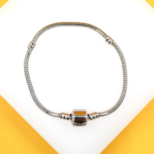 A silver snake chain charm bracelet rests on a white and yellow display surface.