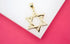A polished gold Star of David pendant rests on a white display surface against a vibrant pink background.