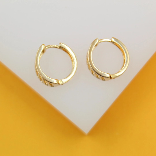 A pair of polished gold hoop earrings rests neatly on a white and yellow display surface.
