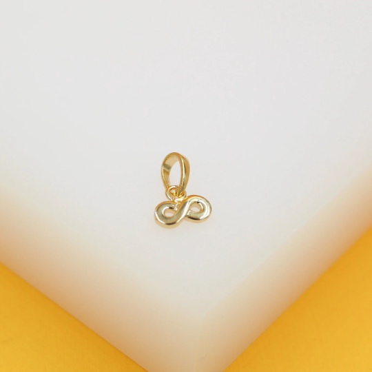 A polished gold infinity pendant rests on a white display block.