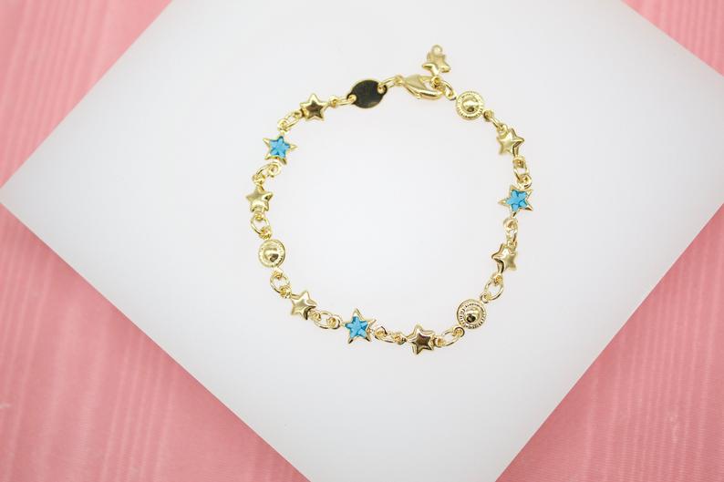 A delicate gold charm bracelet featuring alternating star and circular motifs rests on a white display surface.