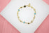 A delicate gold charm bracelet featuring alternating star and circular motifs rests on a white display surface.