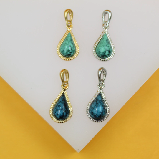 Four teardrop-shaped turquoise stone pendants display in gold and silver settings on a white display stand.