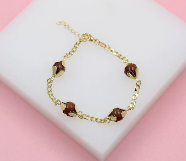 A delicate gold-plated chain bracelet featuring sparkling brown sandstone bead charms nestled in flower-like settings rests on a white display surface.