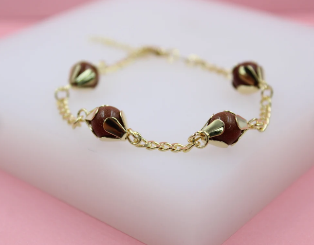 A delicate gold chain bracelet features sparkling brown sandstone bead charms cradled in decorative golden settings.