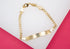 A polished gold ID bracelet with a curb chain rests on a white and pink display surface.