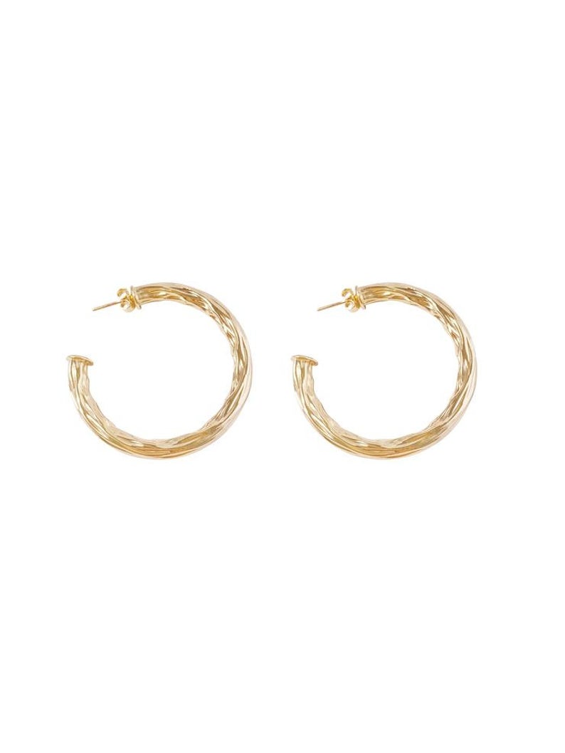 A pair of textured gold hoop earrings displays a twisted, organic design against a clean white background.