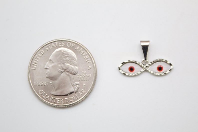 A silver double-eye evil eye pendant rests next to a US quarter coin to show its small scale.