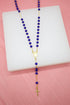 A Catholic rosary necklace featuring vibrant blue beads and a gold chain, centerpiece, and crucifix lies displayed on a white surface against a pink background.