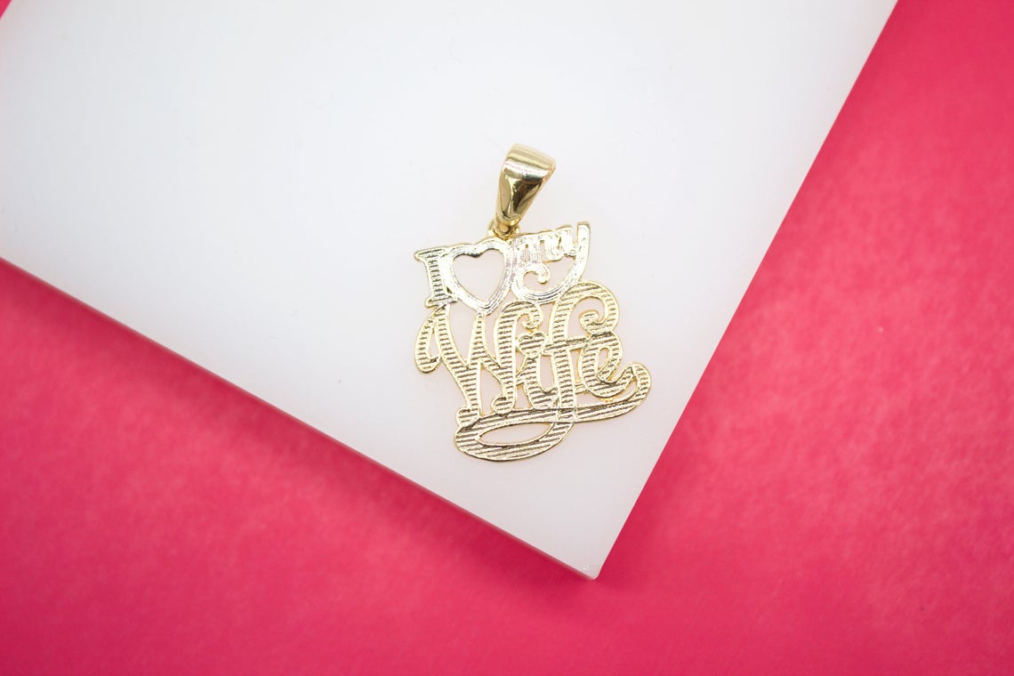 A gold "I Love My Wife" pendant rests on a white and pink display surface.