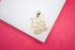 A gold "I Love My Wife" pendant rests on a white and pink display surface.