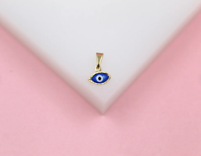 A delicate gold evil eye charm pendant rests on a white geometric display against a soft pink background.